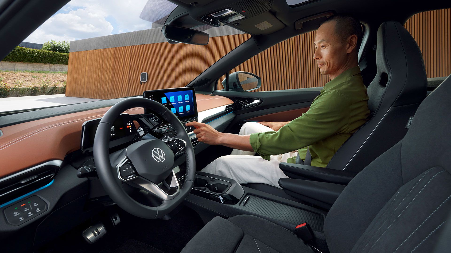 Seitlicher Blick auf die Vordersitze eines VW ID.5, auf dem Vordersitz bedient ein Mann das Infotainment-System