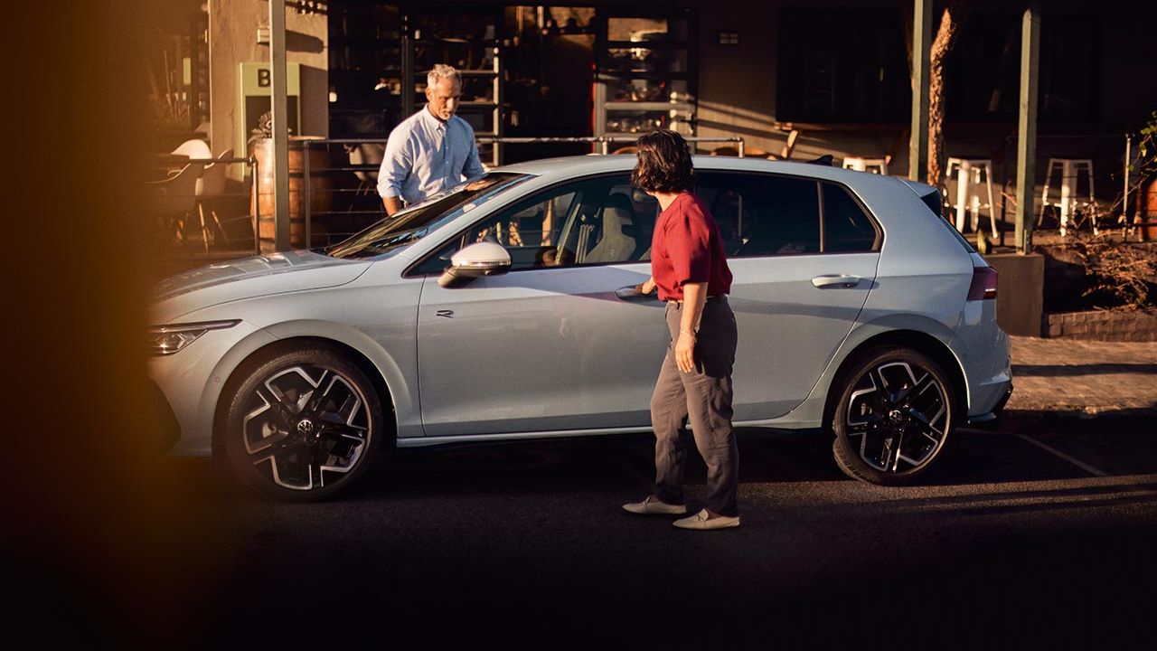 Ein Mann und eine Frau steigen in einen VW Golf ein 