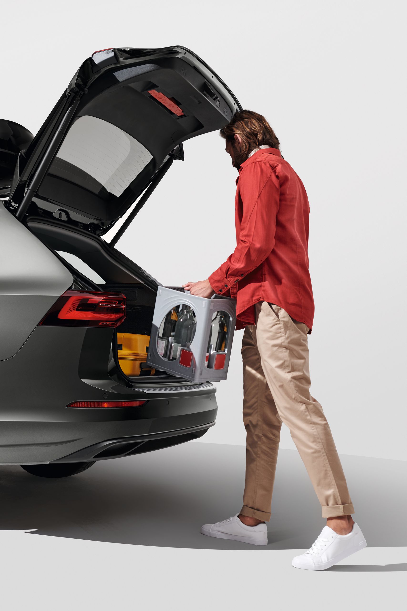 Ein Mann belädt den Kofferraum eines Volkswagen Golf Variant