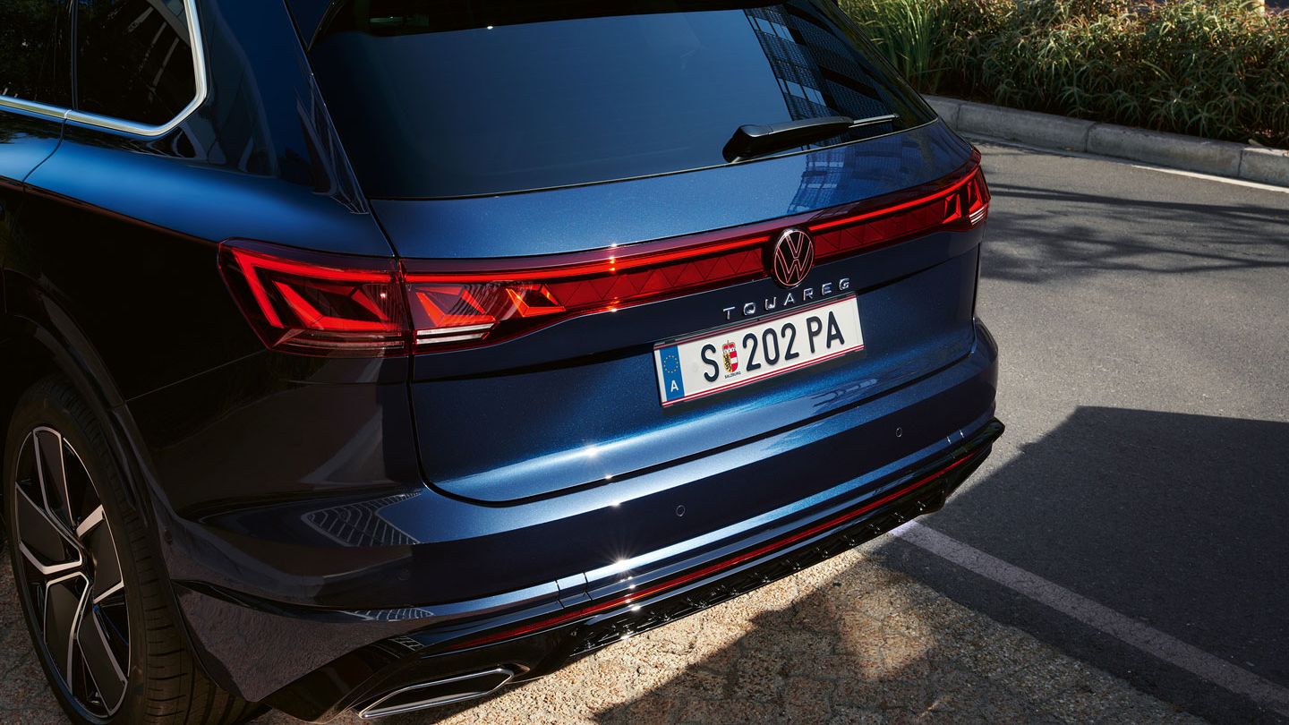 Blick auf das Heck des VW Touareg R-Line mit LED-Rückleuchten, Lichtleiste und illuminiertem VW Logo.