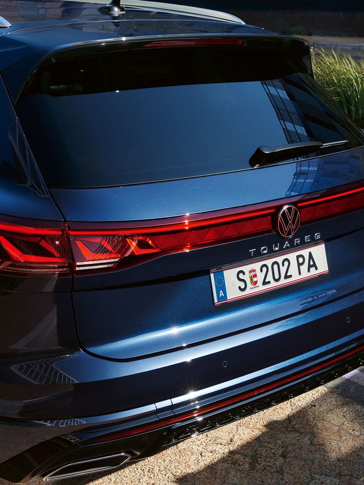 Blick auf das Heck des VW Touareg R-Line mit LED-Rückleuchten, Lichtleiste und illuminiertem VW Logo.