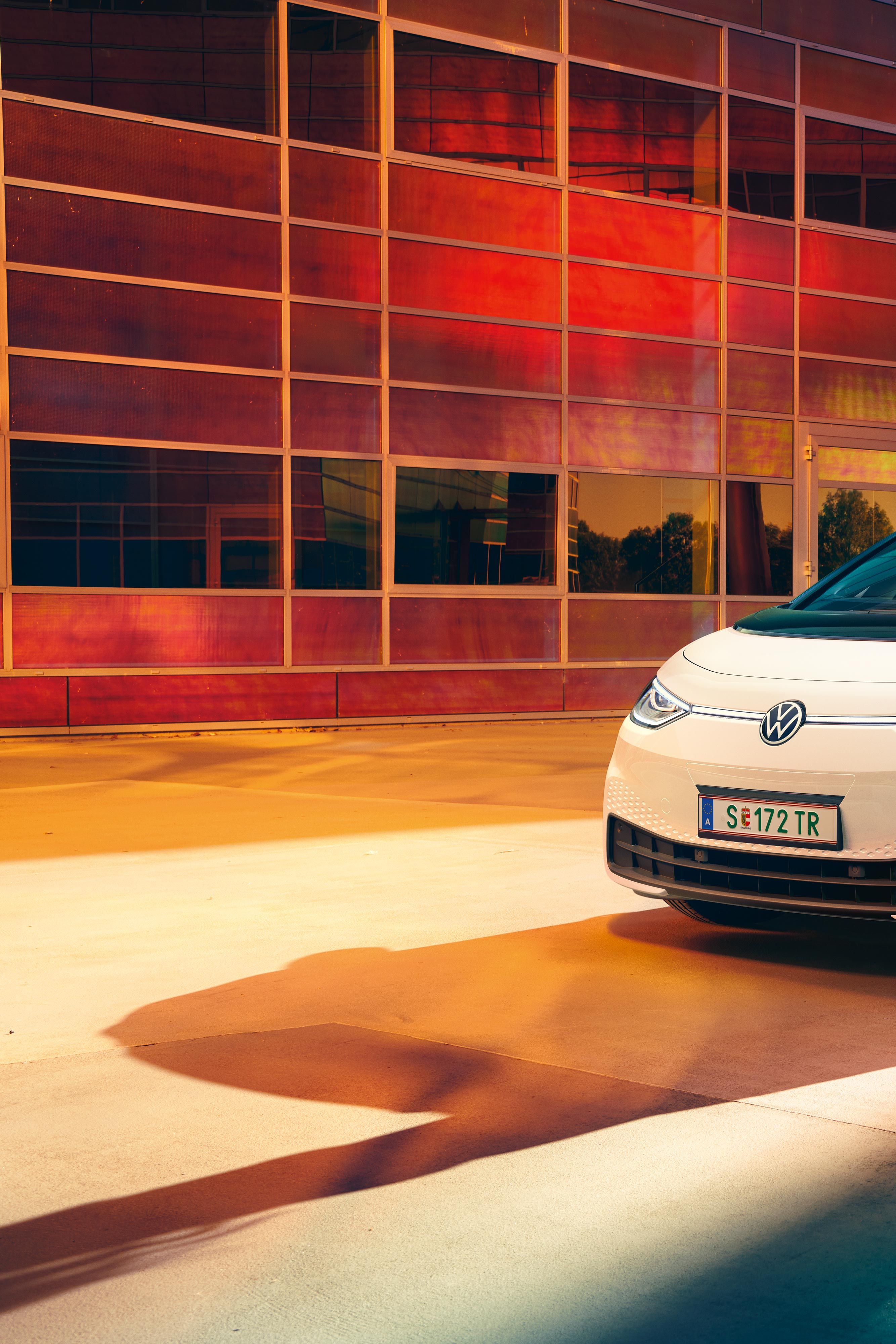 Frau vor dem weißen Volkswagen ID.3, Sicht auf das Fahrzeug von vorne rechts