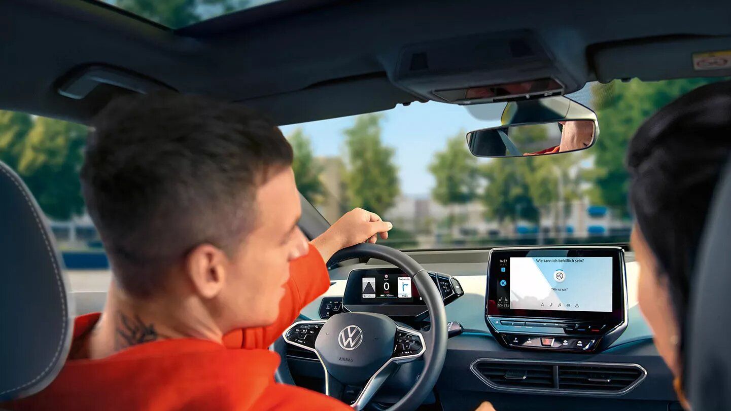 Personen auf den Vordersitzen im VW ID.3 schauen sich das Radiodisplay an