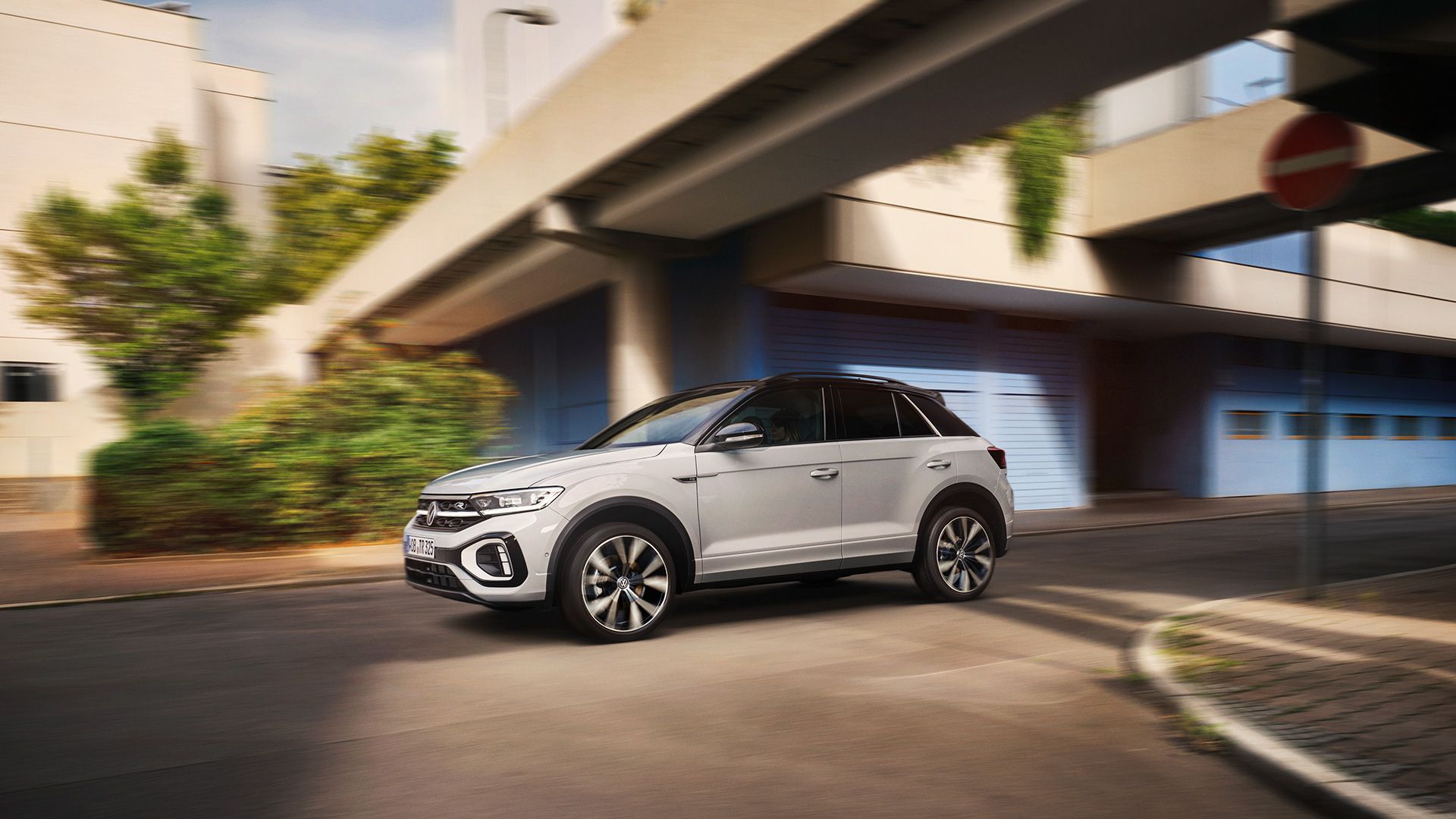 VW T-Roc R-Line in weiß fährt dynamisch über Kreuzung, von der Seite zu sehen