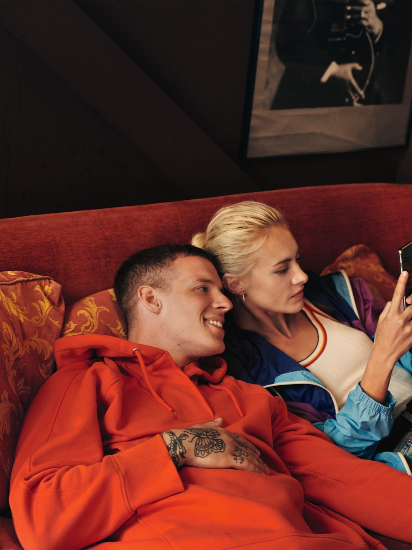 Mann und Frau liegen gemutlich auf einem Sofa und schauen aufs Smartphone