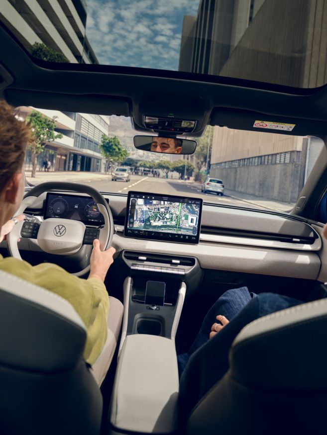 Ein Mann fährt einen VW ID. Polo Style, auf dem Beifahrersitz eine Frau die lacht. Durch das Panoramadach sind Hochhäuser zu sehen