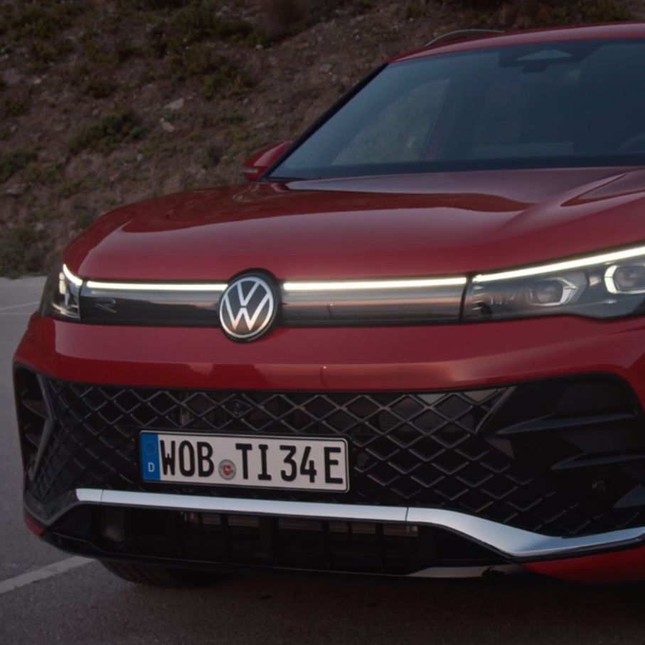 Detailansicht der Front-Lichtsignatur eines auf einem Parkplatz stehenden roten VW Tiguan.