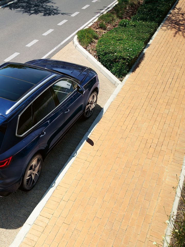 Ein VW Touareg R-Line parkt am Straßenrand, Ansicht von schräg oben auf das Heck und Panoramaglasdach.