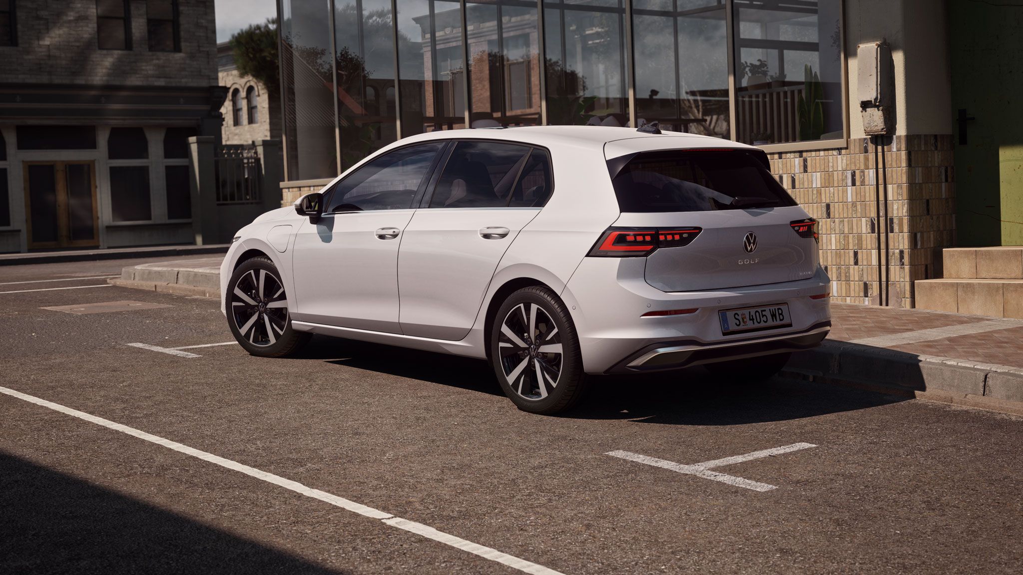 Seiten- und Heckansicht eines weißen VW Golf eHybrid der in Stadt geparkt ist
