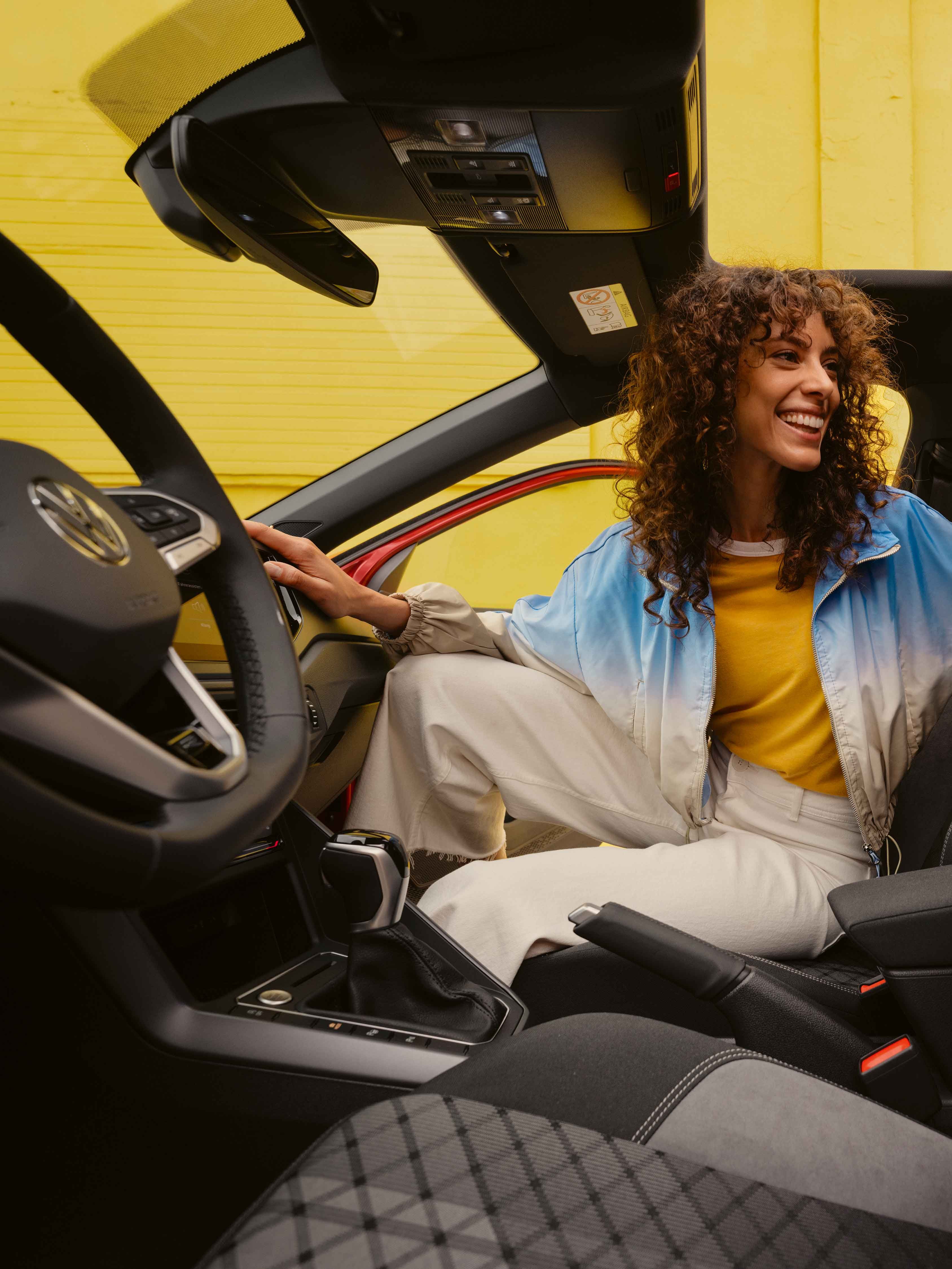 VW Taigo R-Line Interieur: Frau sitzt auf Beifahrersitz und schaut nach hinten