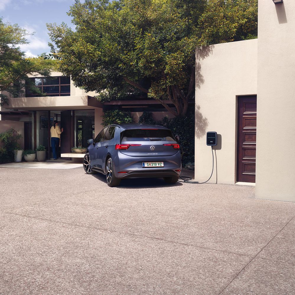 Ein blauer VW ID.3 Neo lädt an einer Wallbox vor einem Einfamilienhaus