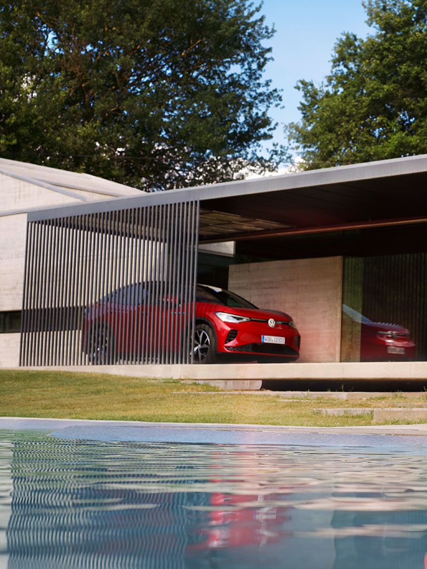 Roter VW ID.5 GTX parkend vor einem Haus. Eine Frau im roten Kleid am Pool.
