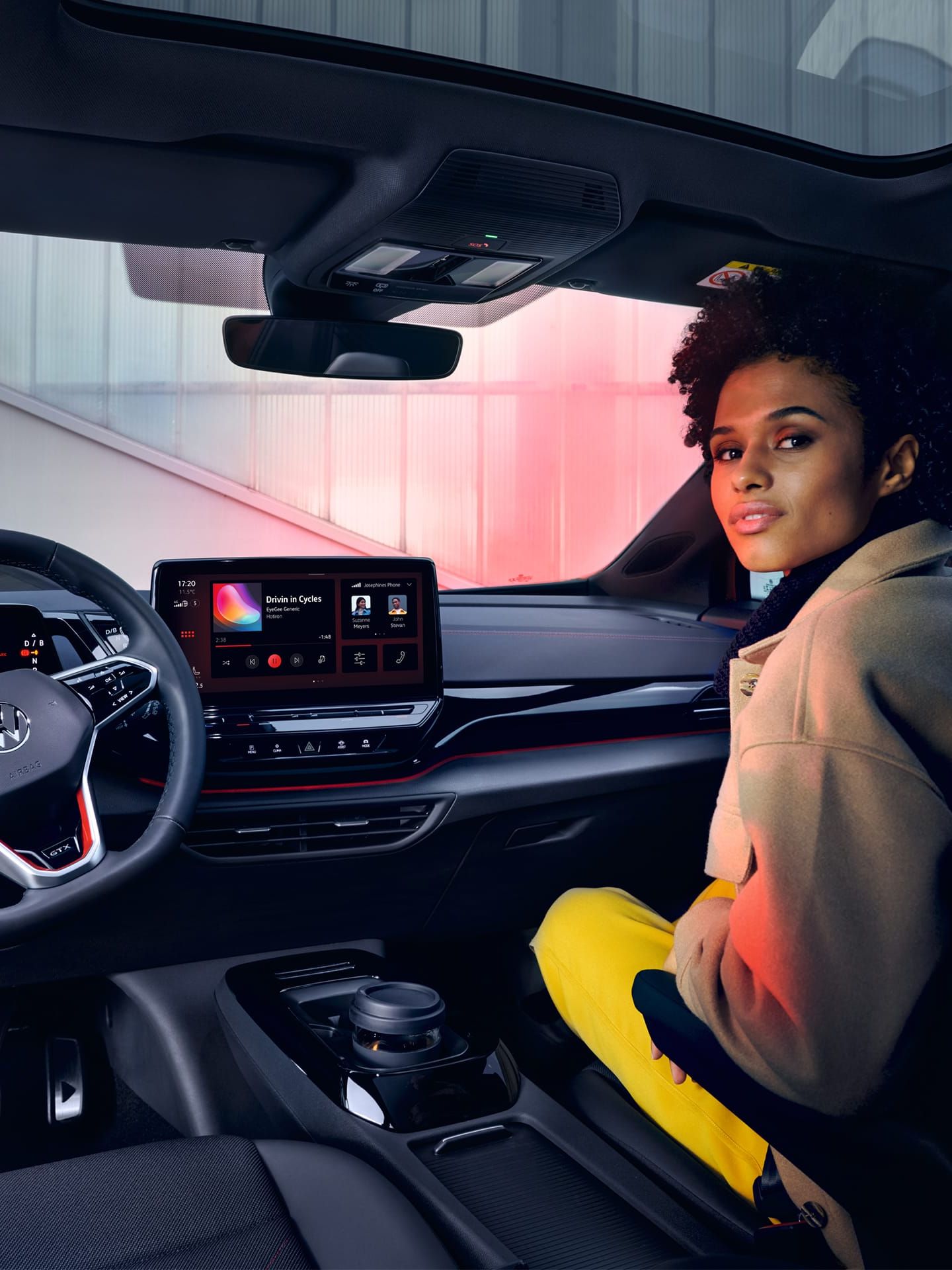VW ID.4 GTX Innenraum mit Blick auf die Vordersitze und Cockpit. Frau sitzt auf Beifahrersitz mit Blick nach hinten.