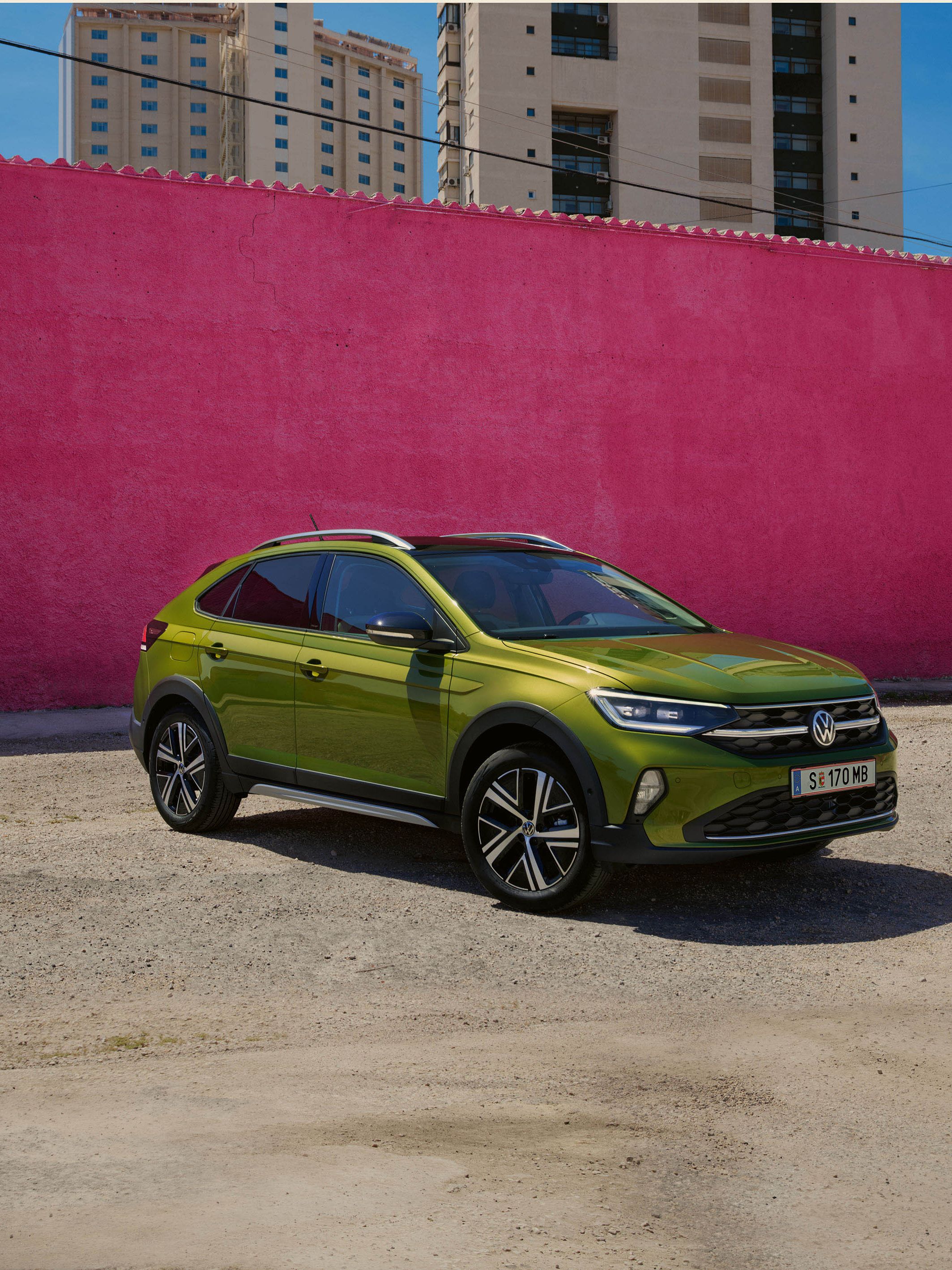 VW Taigo Style Front- und Seitenansicht in Grün auf Parkplatz vor pinkem Gebäude
