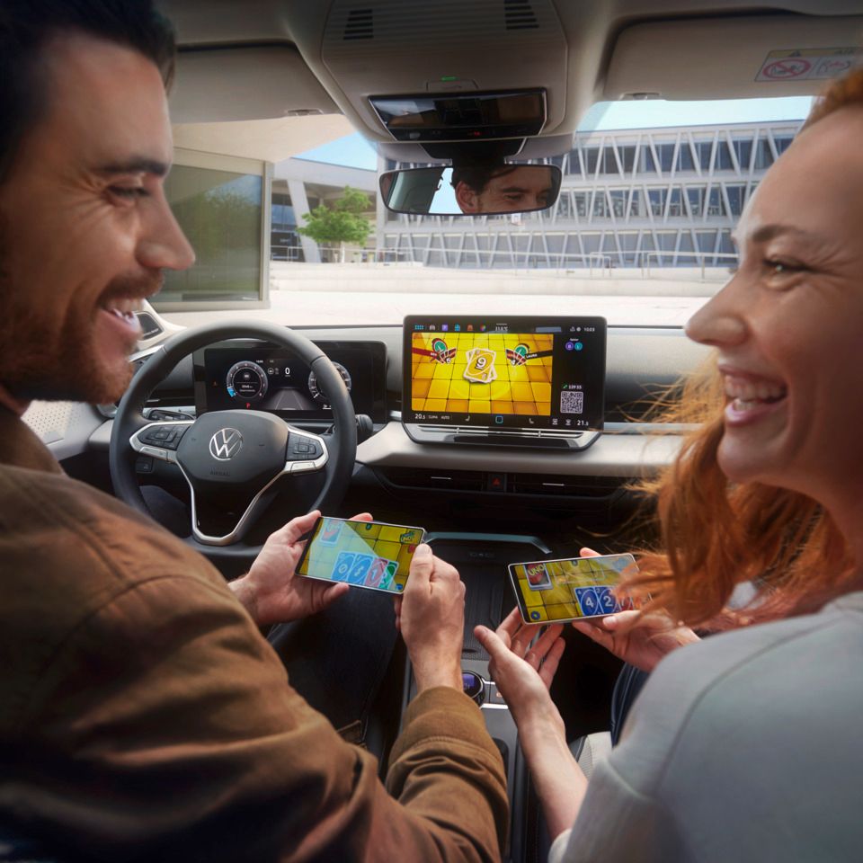 Ein Paar im VW T-Roc Style spielt Uno via AirConsole mit Smartphones als Controller..