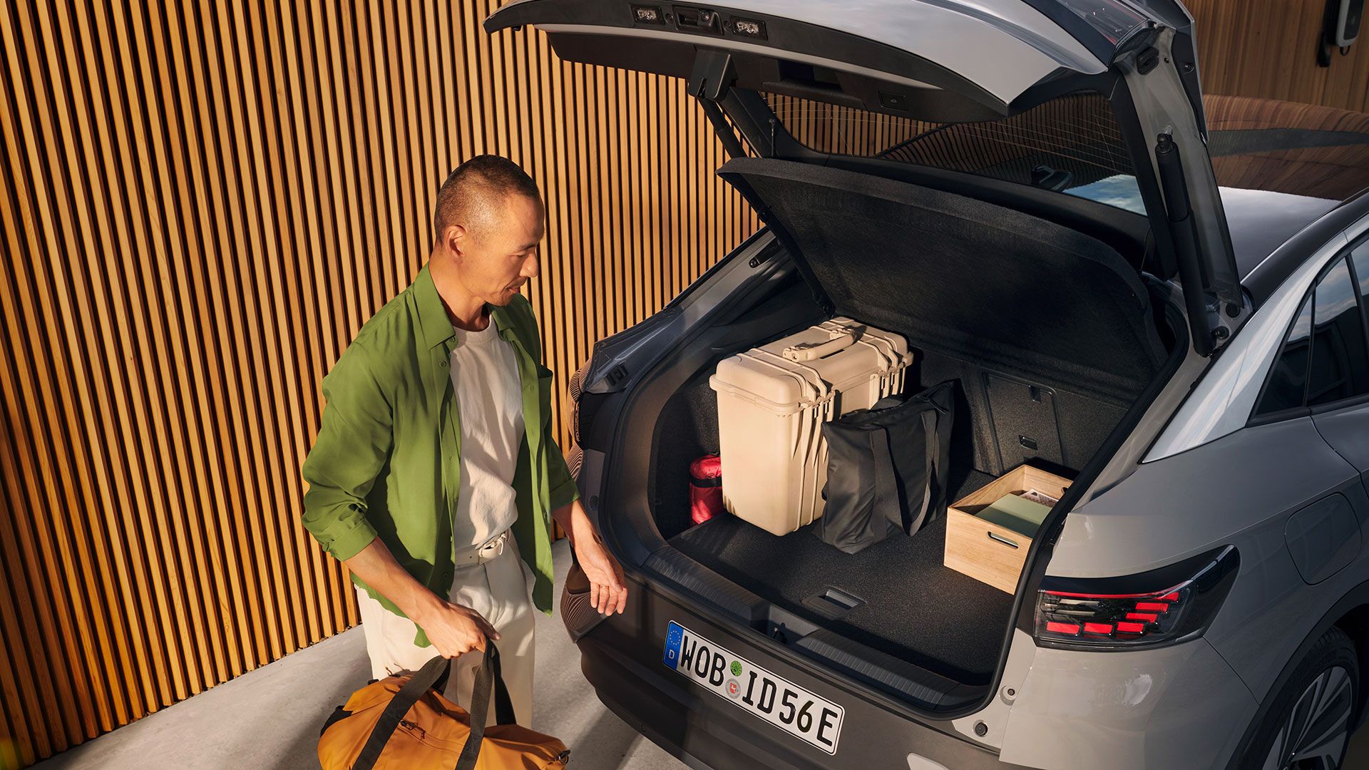 VW ID.5 mit geöffnetem Kofferraum und Gepäck darin, unter der offenen Heckklappe steht ein Mann mit einer Tasche in der Hand