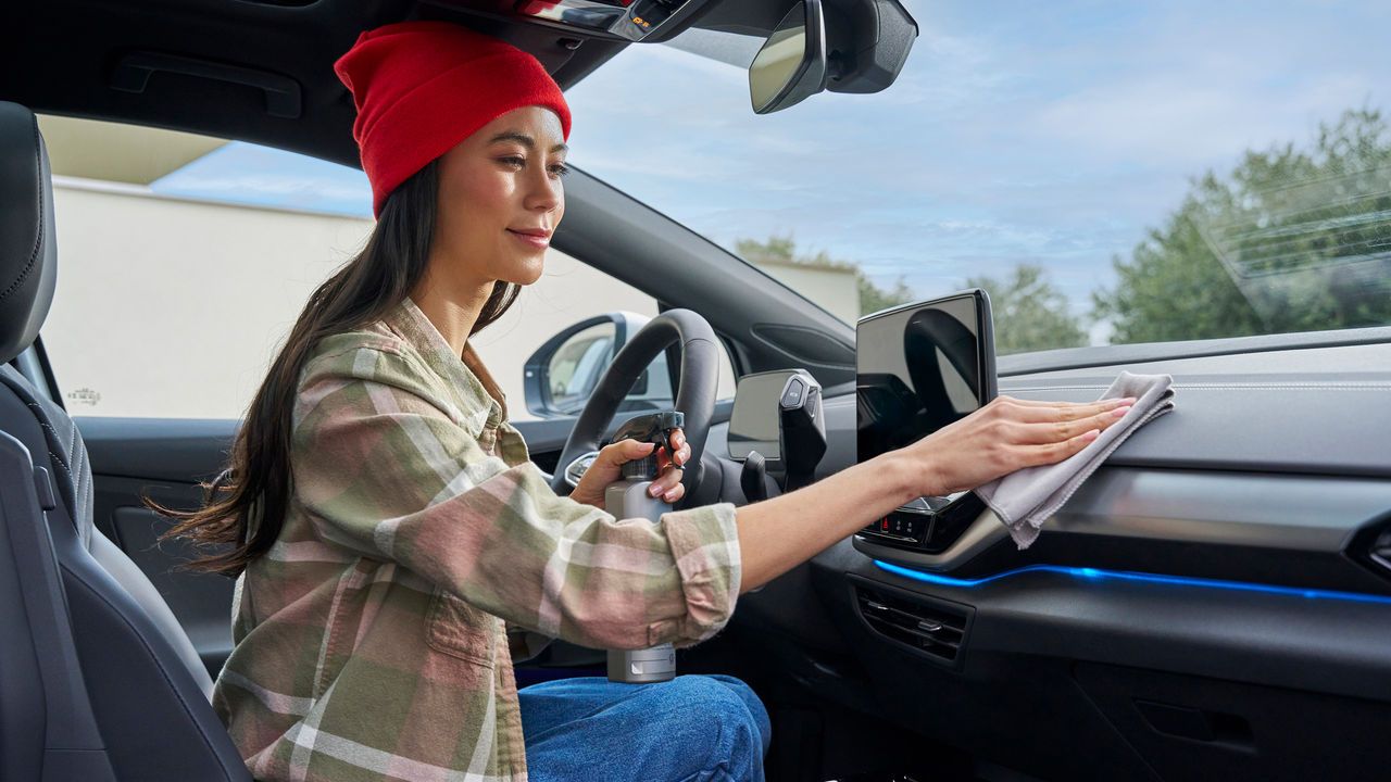 Eine Frau putzt das Cockpit in ihrem Volkswagen