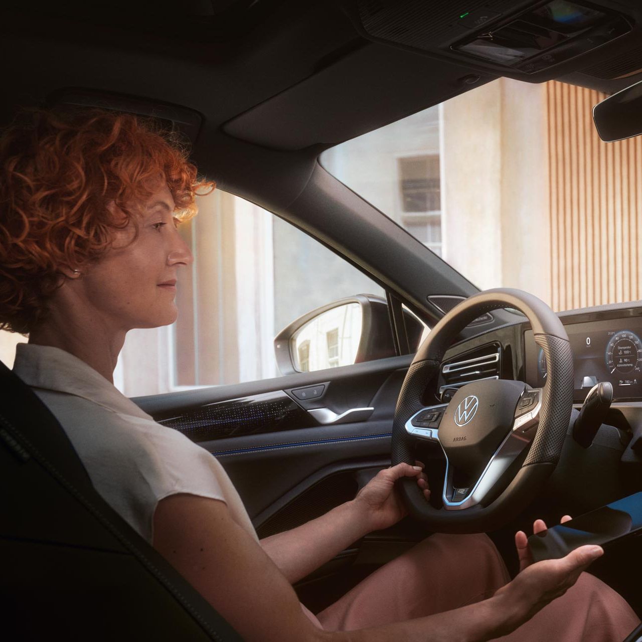 Eine Frau sitzt am Steuer des VW Passat in Interaktion mit der optionalen App-Connect und ihrem Smartphone.
